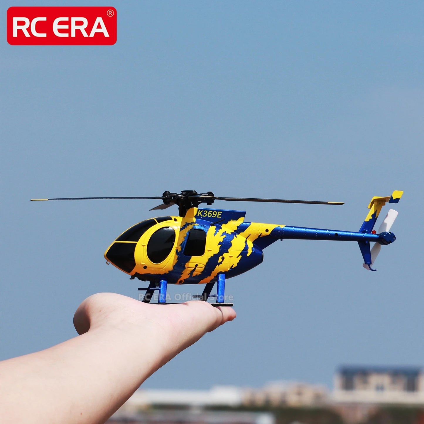 Yellow and blue toy helicopter held in a hand with a clear blue sky background