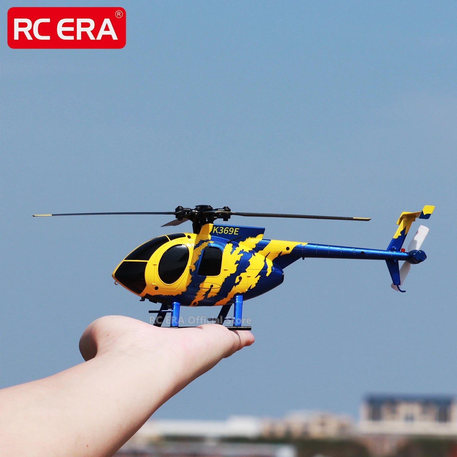 Yellow and blue toy helicopter held in a hand with a clear blue sky background