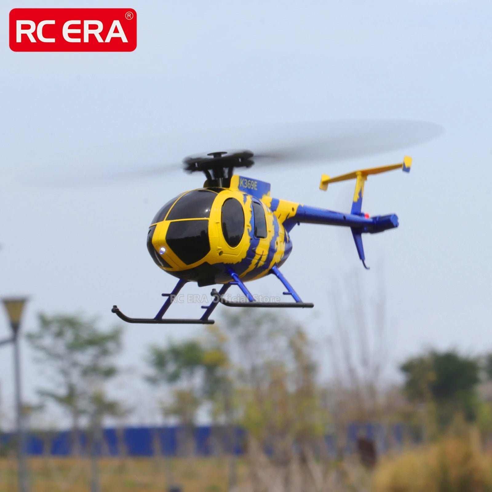 Yellow and blue RC helicopter flying against a blurred outdoor background with RC ERA branding.