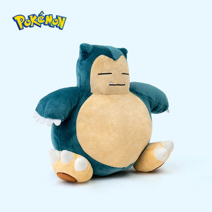 Snorlax plush toy with a blue and beige color scheme on a light gray background, featuring the Pokémon logo.