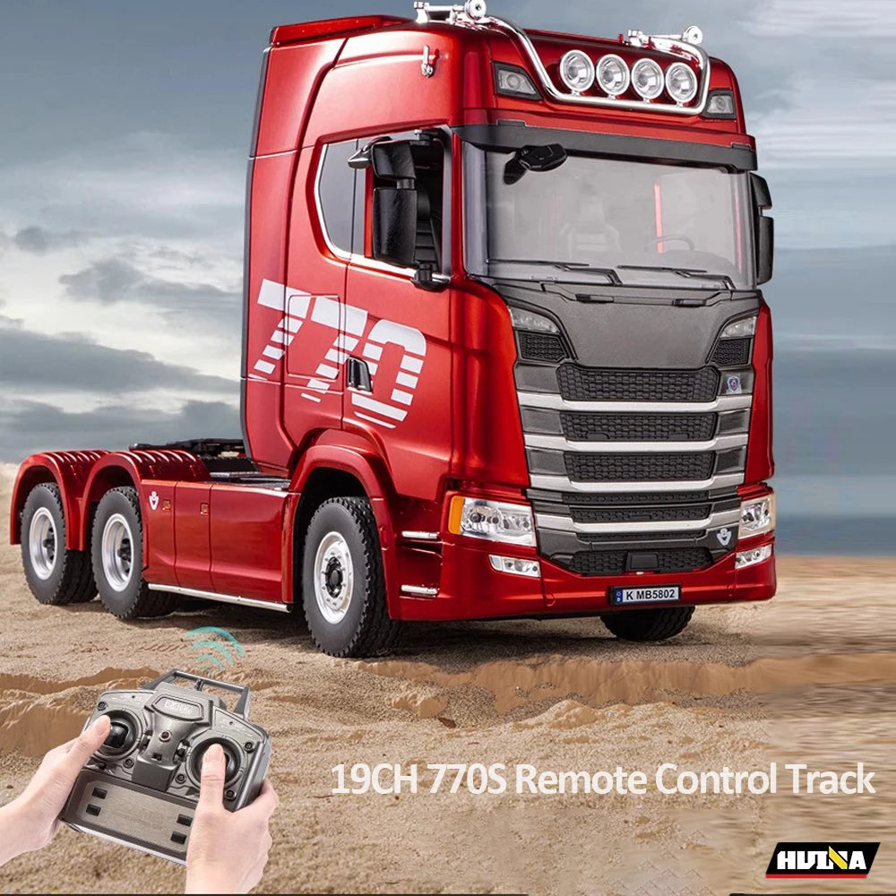 Red remote control truck with a person holding a remote on a sandy surface
