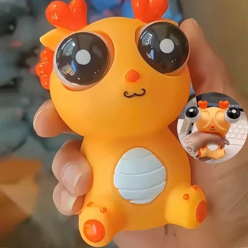 Toy figure of a yellow creature with large black eyes and orange accents held in a hand.