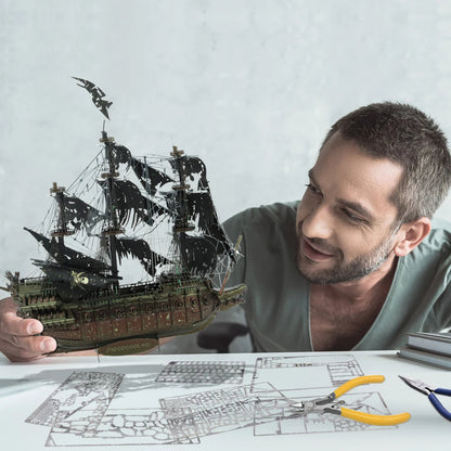 Man holding a model ship with blueprints and tools on a table