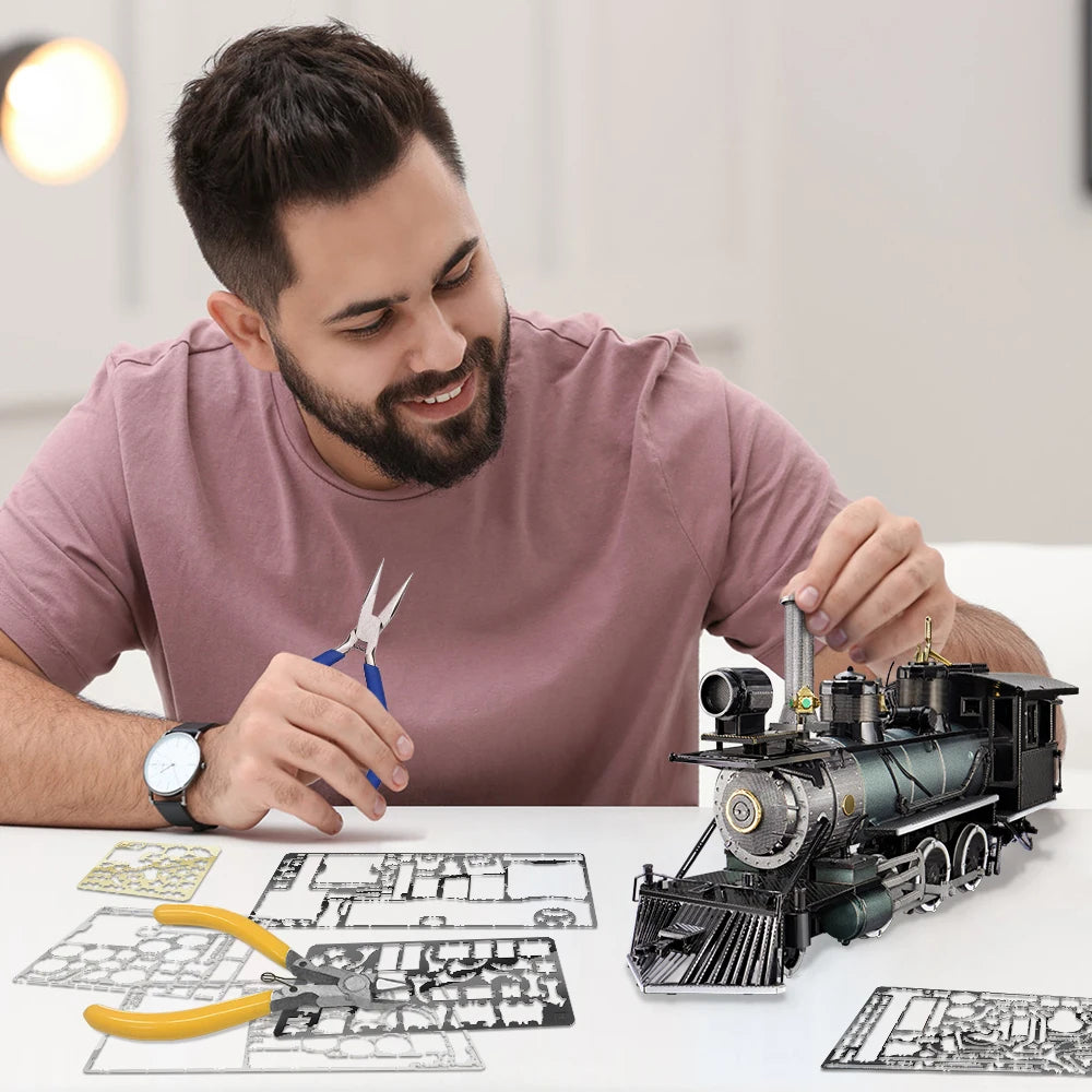 Man assembling a model train set with tools and blueprints on a table.