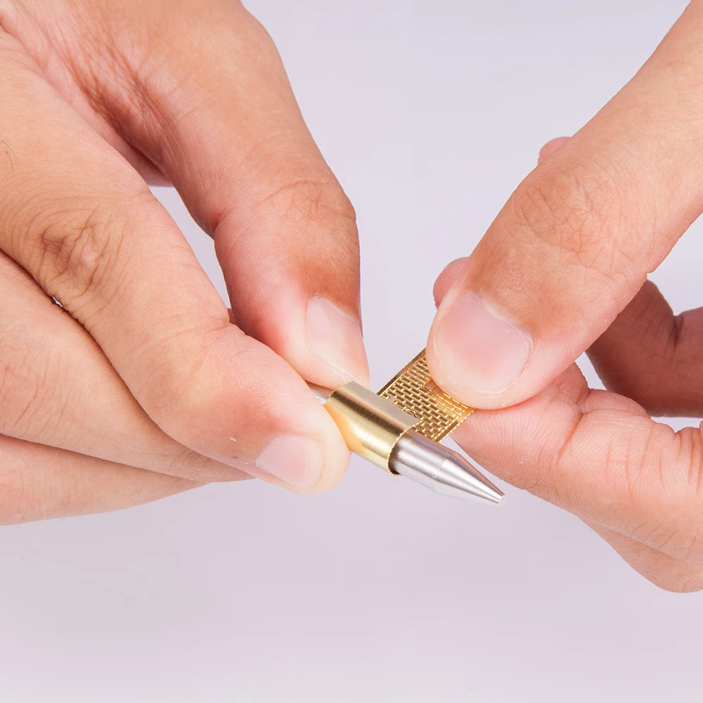 Close-up of hands holding a small metallic tool against a light background