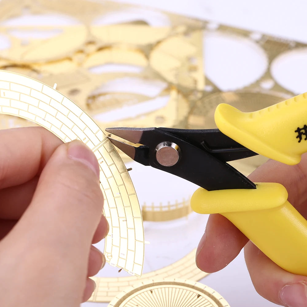 Person using a yellow and black tool to cut a gold circular object on a white background