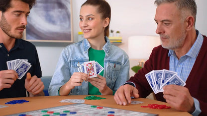 Three people playing cards around a table in a living room setting.
