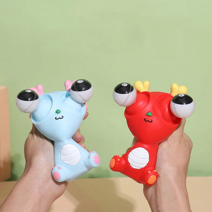 Two colorful plush toys, one blue and one red, held by hands against a green background.