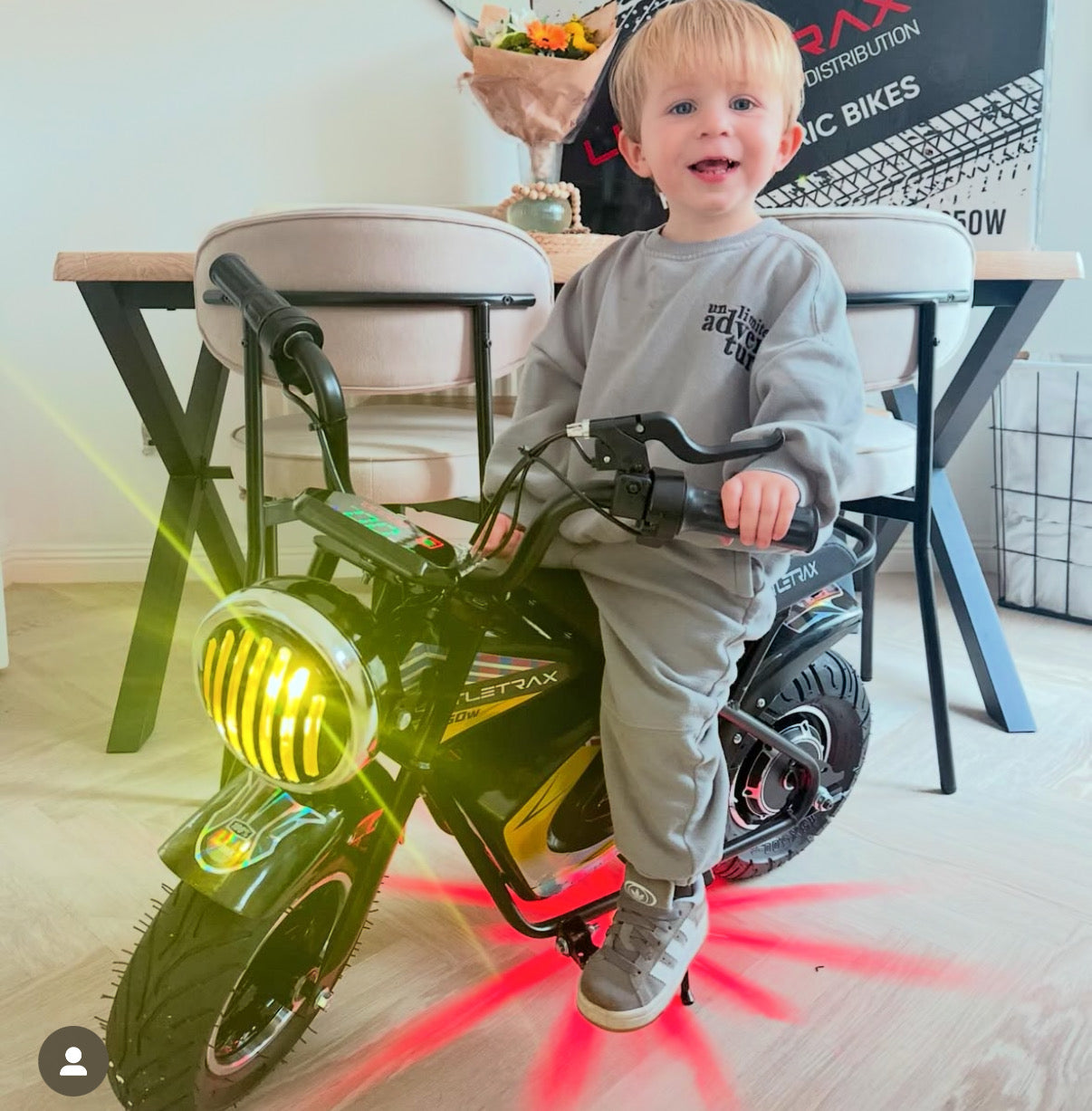 Littletrax 350W Kids Electric Bike Child sitting on a toy bike with glowing lights in a room.