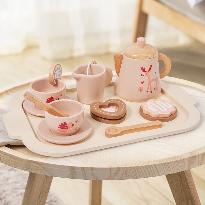 Wooden toy tea set with pink teapot, cups, and cookies on a wooden tray.