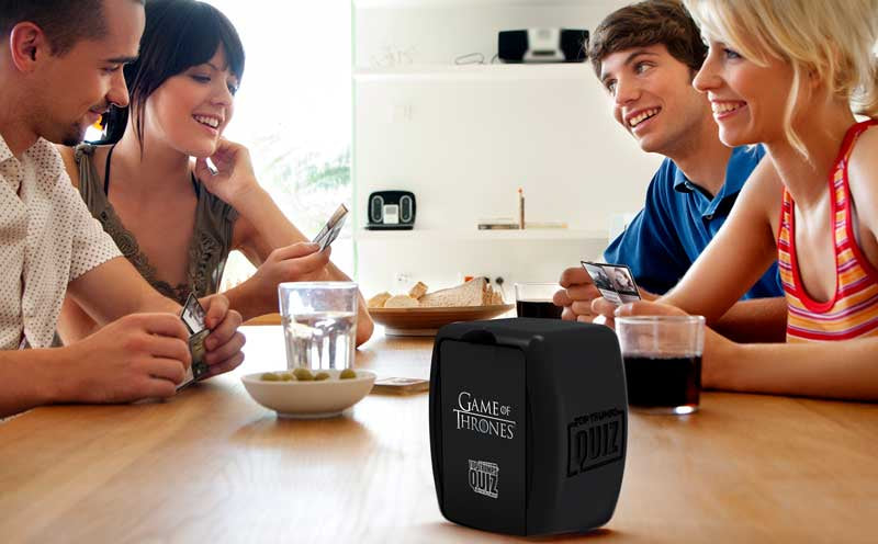 Game of Thrones Top Trumps Quiz | 500 Questions Across All 8 Seasons Group of people sitting around a table with a 'Game of Thrones' themed product in the foreground.