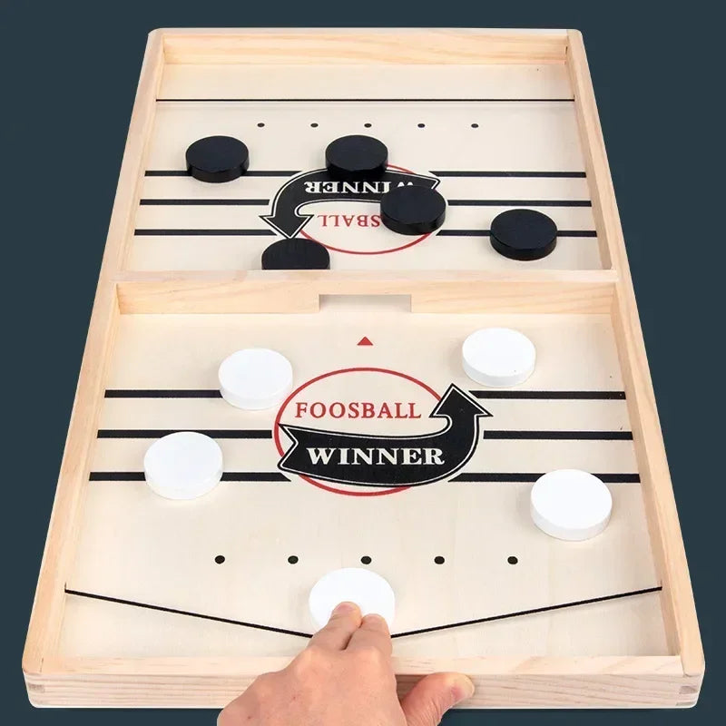 Wooden foosball table game with a hand interacting with it on a dark background