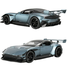 A 1:32 scale diecast replica of an Aston Martin Vulcan supercar, depicted from two angles showing the front and side profiles. The model has a blue color with black details and features such as a gullwing door, rear wing, and realistic tire tread.