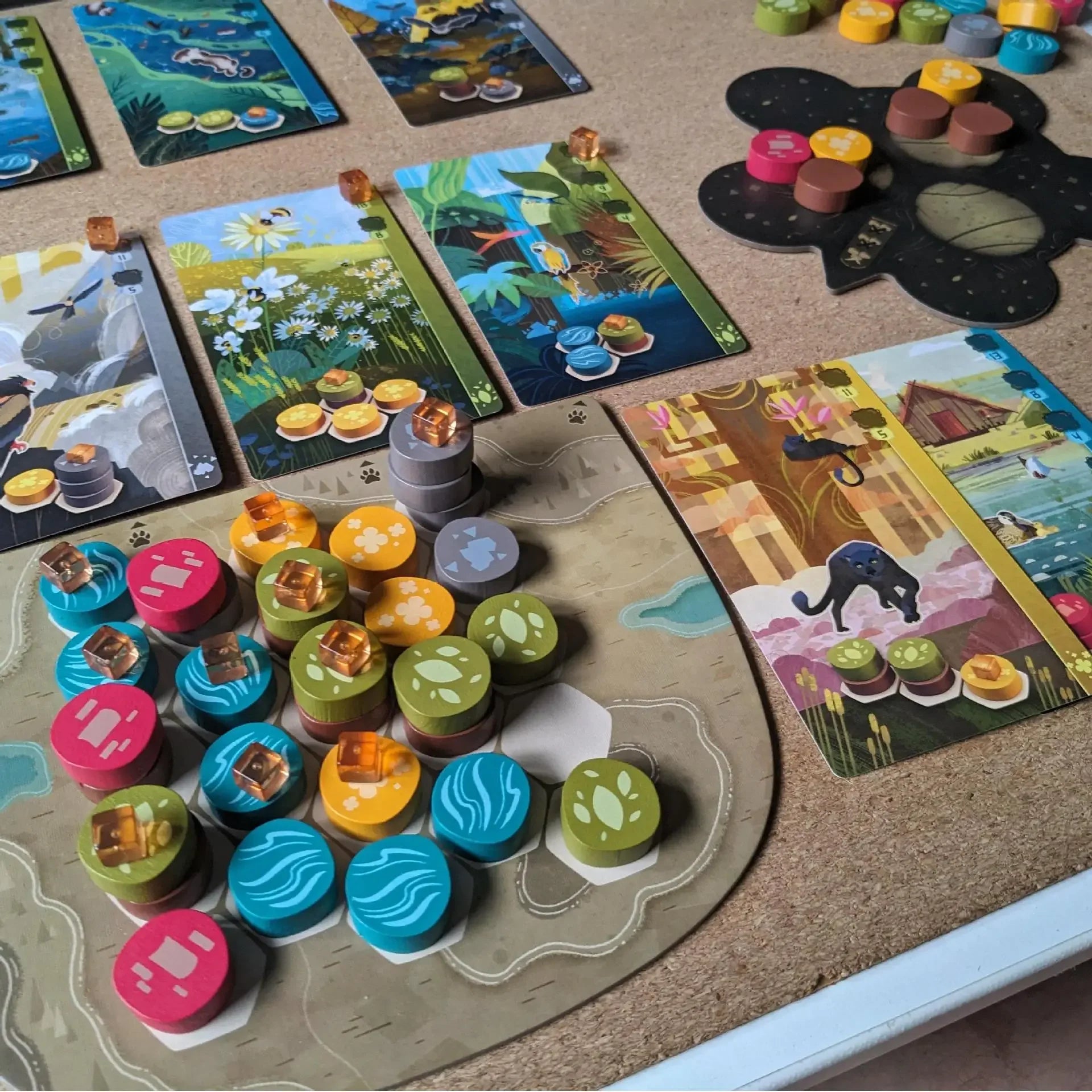 Board game with colorful tiles and pieces on a cork board surface