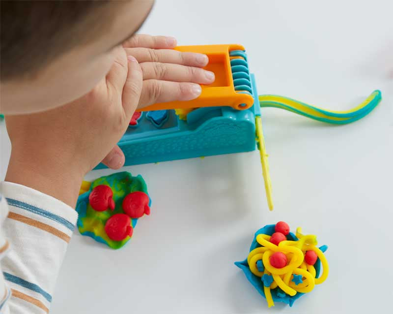 Child playing with a colorful toy on a white surface