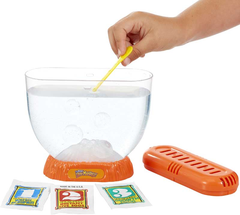 Science experiment kit with a clear bowl, ice cube, and colorful packets on a white background